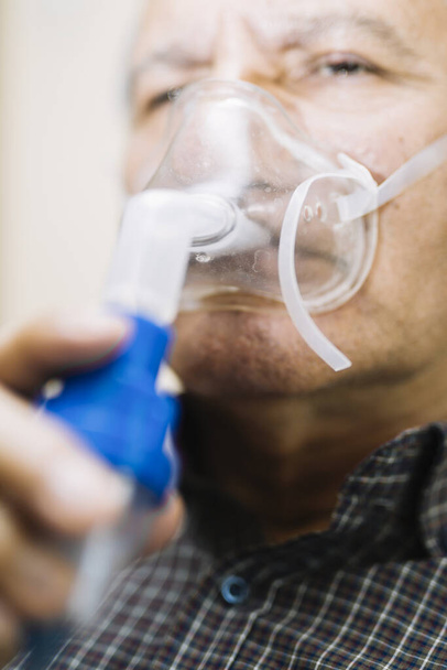 Vanhempi mies käyttää lääketieteellisiä laitteita hengitysteiden naamio, sumutin huoneessa
 - Valokuva, kuva