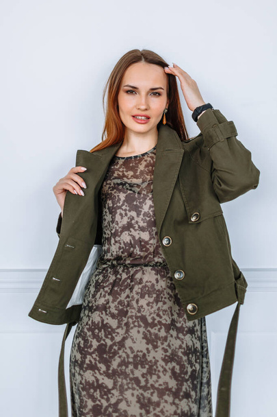 A model girl in a light dress and a green jacket. Demonstration of clothing for the showroom - Foto, imagen