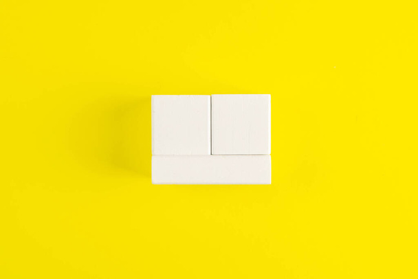Cubos de madeira branca isolados sobre um fundo amarelo. Está alinhado para caber num quarto, mês e data. Vista frontal
. - Foto, Imagem