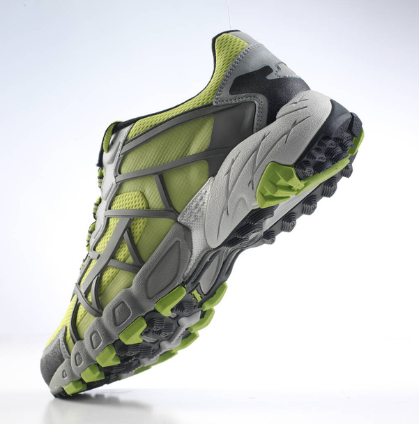 Дизайн зеленой и серой удобной спортивной обуви с текстурированной резиновой подошвой наклона на белом фоне
 - Фото, изображение