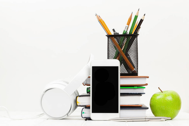 Mesa de escritorio de oficina con teléfono inteligente, suministros y manzana sobre fondo blanco. Con espacio para tu texto o app - Foto, imagen