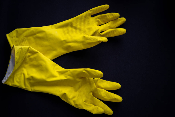 Two yellow rubber gloves on dark black background - Photo, Image