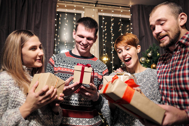 Skupina přátel, mužů a žen, slaví Vánoce. Dávají si dárky, radují se a smějí se. Silvestr. - Fotografie, Obrázek