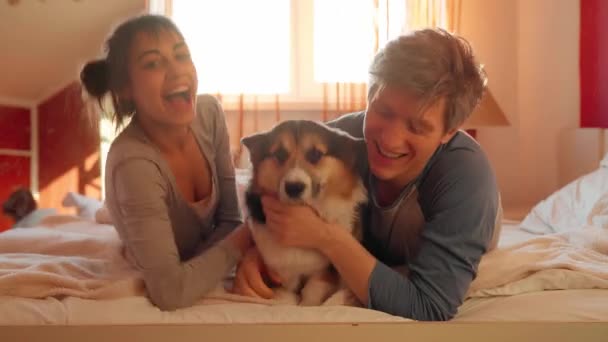 Ευτυχισμένη οικογένεια ξαπλωμένη με σκύλο στο κρεβάτι στο σπίτι - Πλάνα, βίντεο