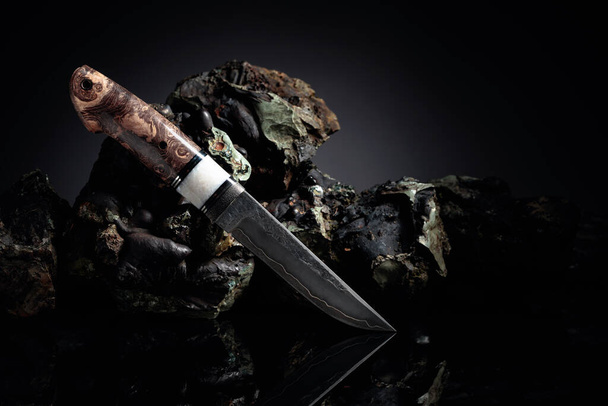 Hunter combat hand made knife and broken stones. The surface of the blade - etching, traces of forging. Handle - inlace acrylester, Japanese maple. Copy space. - Photo, Image