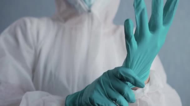 Medic in a protective suit puts on gloves. - Video