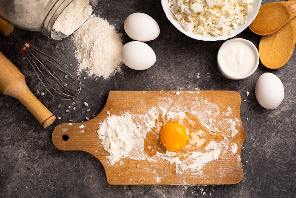 Egg in flour on a wooden board. Cooking homemade dessert. Healthy diet. Top view. - Foto, Imagem