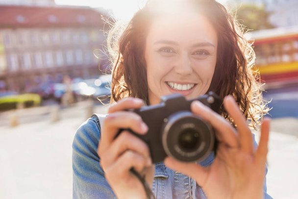 Young attractive woman holding camera and taking photo - Valokuva, kuva