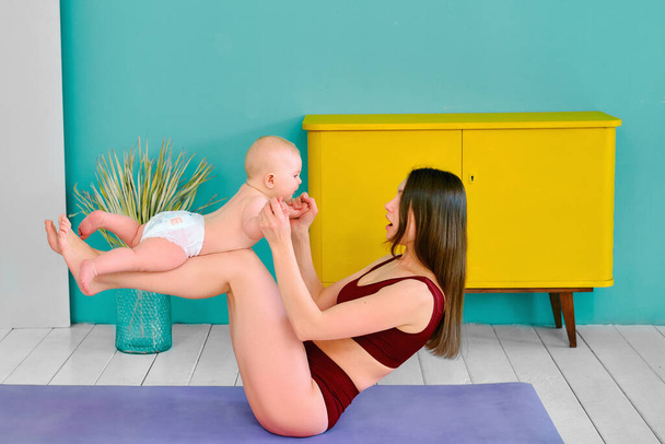 fitness girl practicing yoga at home with a small child - Foto, Imagem