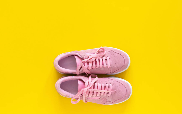 Розовые кроссовки изолированы на желтом фоне
 - Фото, изображение