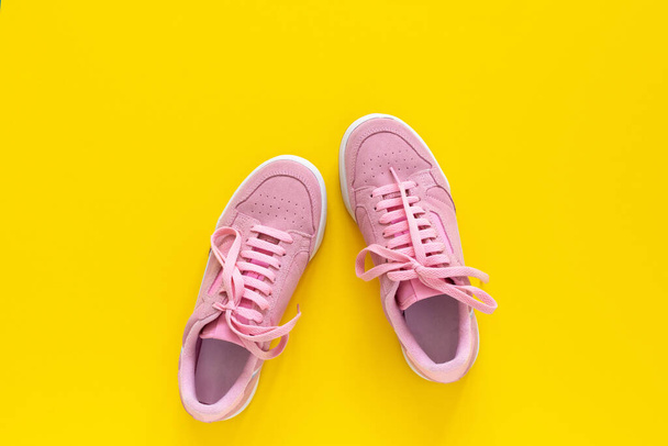 Ροζ αθλητικά παπούτσια απομονωμένα σε κίτρινο φόντο - Φωτογραφία, εικόνα