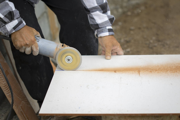 Imagem do trabalhador usando a ferramenta para cortar azulejo branco
. - Foto, Imagem