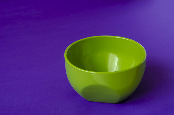 Πράσινο κεραμικό μπολ σε λιλά φόντο. Ένα άδειο μπολ για σούπα ή σαλάτα. Κουζινικά Κοντινό πλάνο. Επιλεκτική εστίαση. - Φωτογραφία, εικόνα