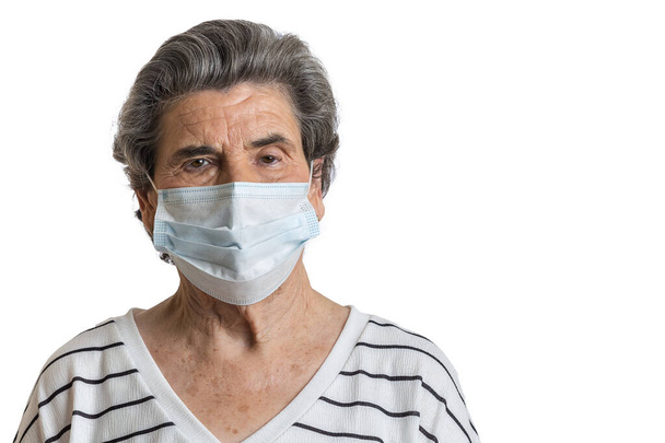 Elderly casual female with short hair protecting with medical mask during pandemic of coronavirus looking at camera - Photo, Image