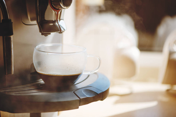 Coffee machine pouring hot espresso in a cup. - Фото, изображение