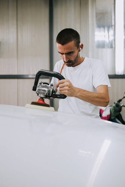 Car detailing - Hands with orbital polisher in auto repair shop. Selective focus. - Foto, Imagen