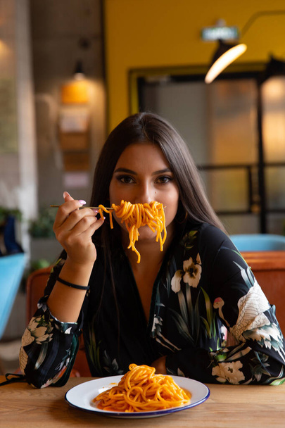 Молода дівчина в кафе їсть макарони
 - Фото, зображення