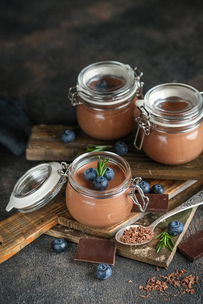 Schokoladenmousse im Glas mit Beeren auf rustikalem Hintergrund. hausgemachtes Dessert. - Foto, Bild