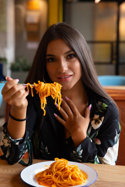 A young girl in a cafe eats pasta - Foto, afbeelding
