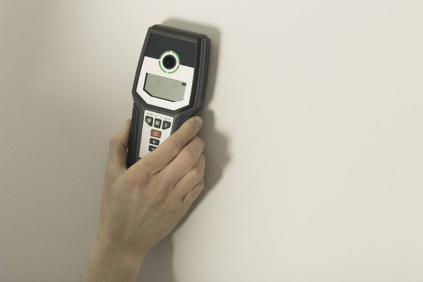 Man hand is scanning wall by cable detector to find a cable before drilling in. - Фото, зображення