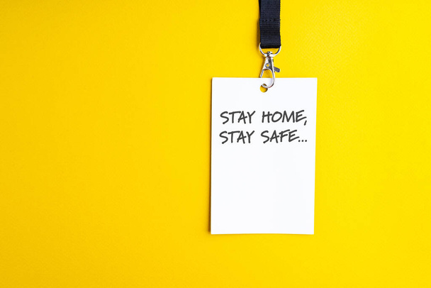 Biała torba papierowa na żółtym tle, smycz z napisem "zostań w domu, bądź bezpieczny", koncepcja pandemii, znak ostrzegawczy - Zdjęcie, obraz