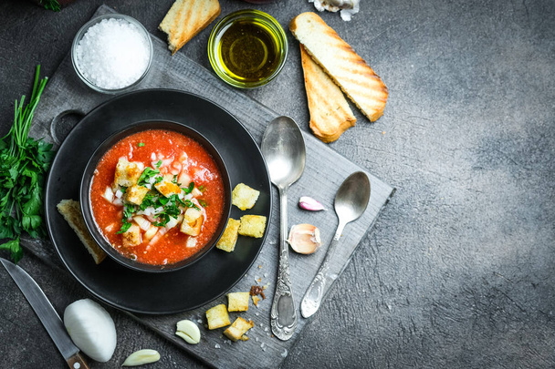 Geleneksel İspanyol soğuk domates çorbası çorbası siyah tahta, taş ya da beton zemin üzerinde bir kasede..  - Fotoğraf, Görsel
