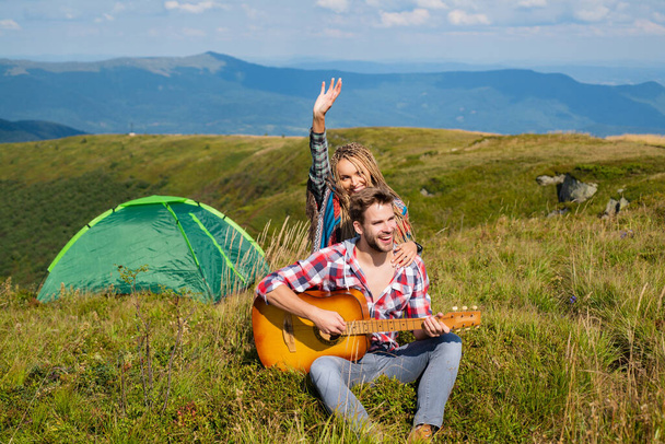 Happy couple friends camping, and playing guitar together in summer at nature forest. Couple in love on camp. - Valokuva, kuva