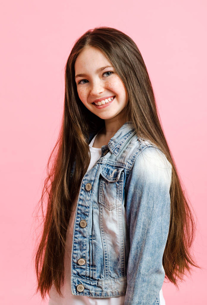 Portrait of adorable smiling little girl child preteen isolated on a pink background - Valokuva, kuva
