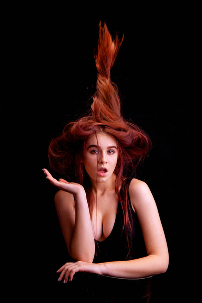 giovane donna in studio su uno sfondo nero con capelli volanti
 - Foto, immagini