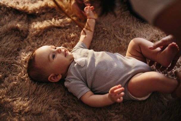 portrait of a child 4 months old lying on the bed and looking. Charming child with dark eyes lying on back, - Foto, imagen