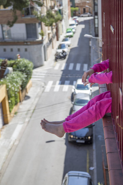 Opgesloten meisje zittend op het balkon van het huis. Even een luchtje scheppen. Ik kijk er naar uit om weer de straat op te gaan. Coronavirusconcept. - Foto, afbeelding