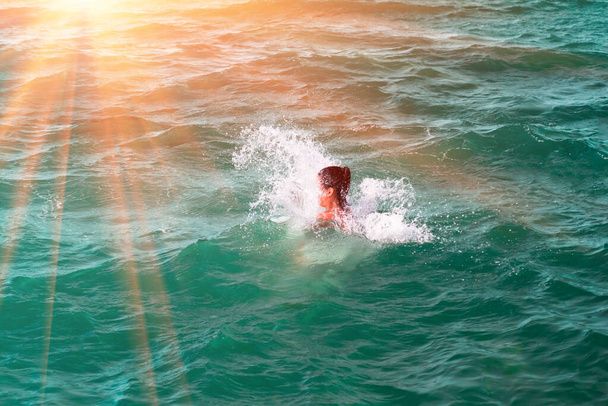 Een meisje verdwijning in een golf, springen en ondergedompeld in een verfrissende zee, oceaan, op een hete zomerdag - Foto, afbeelding