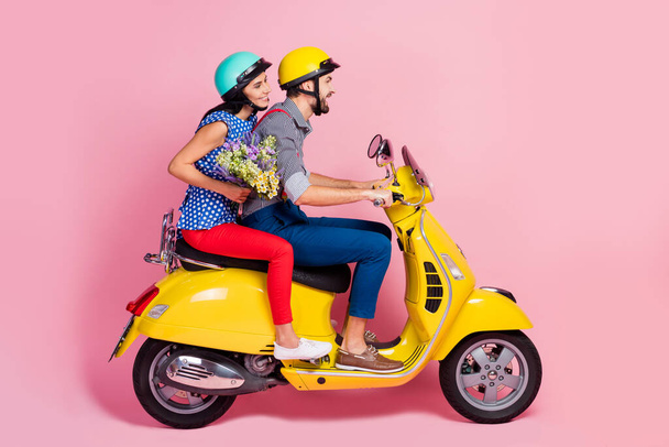 Full length profile side photo of positive cheerful bikers driver rider two people drive motor bike enjoy journey woman hold carry wildflowers bouquet isolated pastel color background - Foto, Imagen