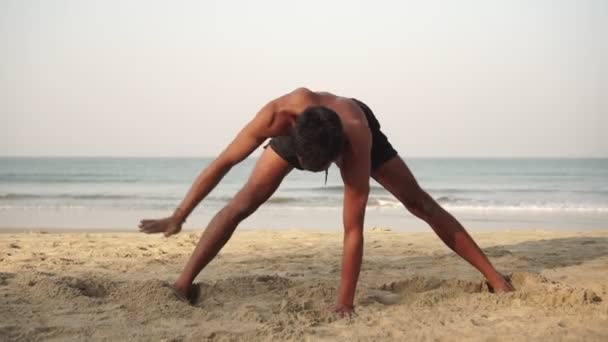 Yoga en meditatie. Portret van een man die yoga beoefent op het strand - Video