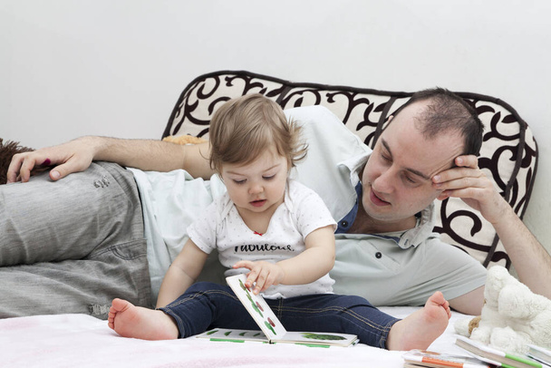 Baba ve kızı kitapları düşünüyor. Babalar Günü konsepti. Çocuklarla evde oyunlar ve aktiviteler - Fotoğraf, Görsel