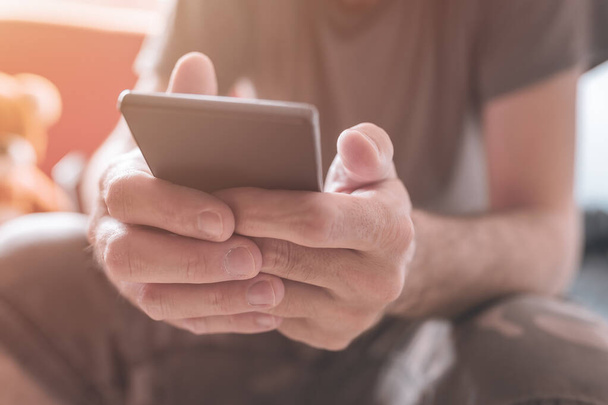 Man using mobile phone at home, close up of male hands addicted to smartphone, selective focus - Photo, image