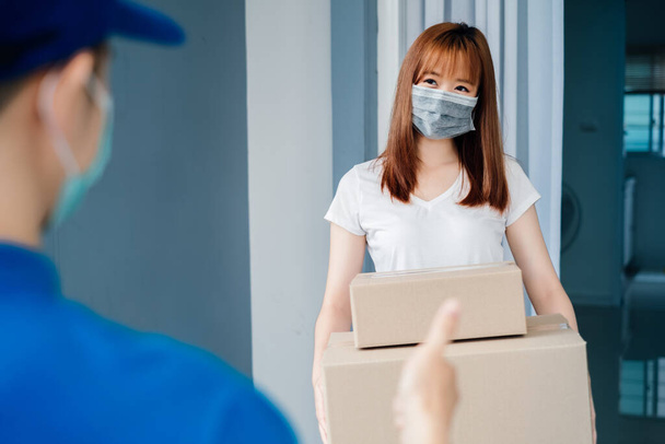 Delivery package asian woman picking carton social distancing thumb up reduce touch and contact infection risk customer receiver shipping deliver shopping online while quarantine at home. - Foto, Imagen
