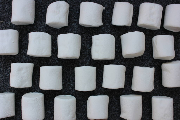 marshmallows op een grijze stenen achtergrond. Fonso snoepjes met plaats voor tekst. Veel geheel witte zoete pluizige marshmallow copyspace plat op grijze steen - Foto, afbeelding