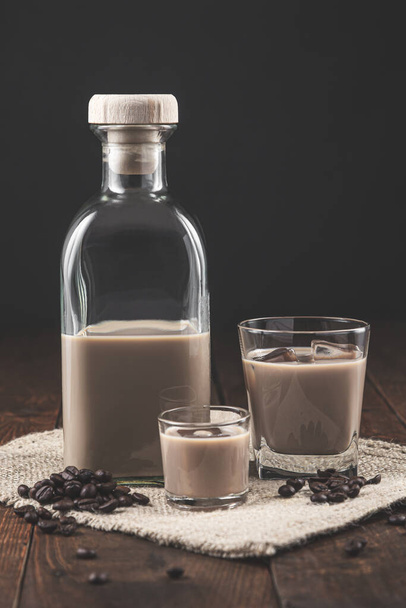 Bottle and glasses of Cream coffee liqueur with ice, and coffee  beans on rustic wooden background. - Foto, Imagem