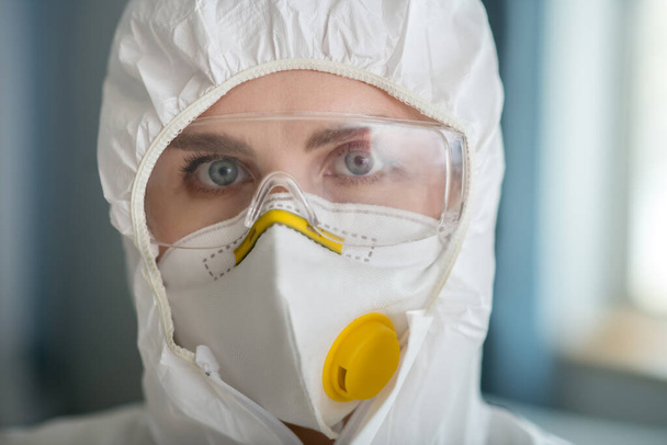 Woman in white workwear and protective eyeglasses looking determined - Fotoğraf, Görsel
