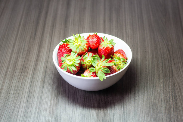 Photo session of fresh organic strawberries. It also includes gray wood textures and a white bowl. The combination of bright colors stands out. - Photo, Image