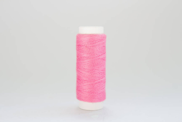 carrete de hilo rosa sobre un fondo blanco
 - Foto, imagen