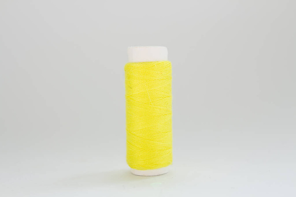 spool of yellow thread on a white background - Foto, immagini