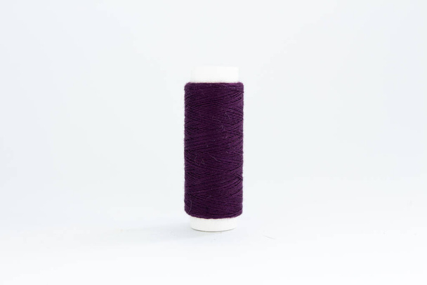 spool of purple thread on a white background - Фото, изображение