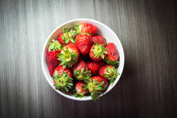 Photo session of fresh organic strawberries. It also includes gray wood textures and a white bowl. The combination of bright colors stands out. - Photo, Image