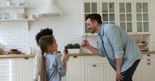 Father and two mixed race kids dancing singing in kitchen - Filmagem, Vídeo