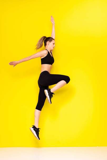 young athletic woman doing sport on yellow background - Foto, Imagem