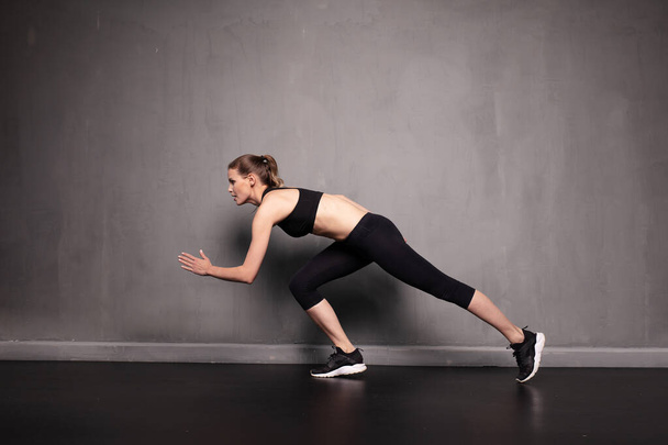 young athletic woman doing sport on grey industrial wall - Φωτογραφία, εικόνα