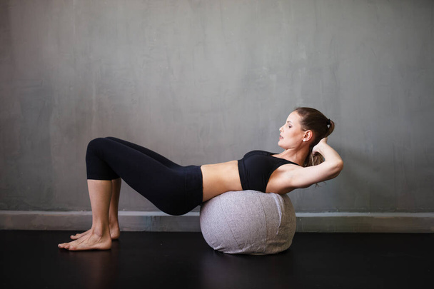 athletic woman exercising her abs on a ball inside a industrial home - Fotografie, Obrázek