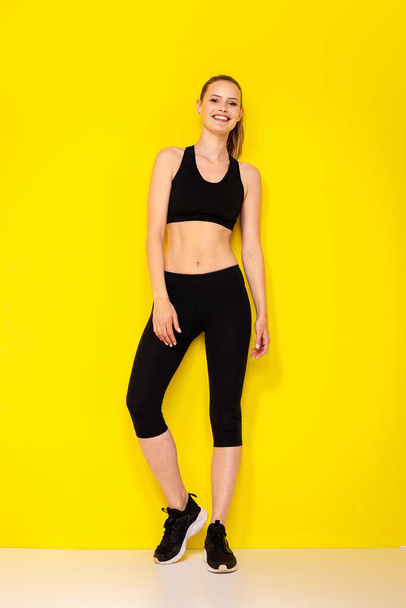 nice and slim fit woman resting on a yellow background in fitness outfit sportwear - Fotoğraf, Görsel